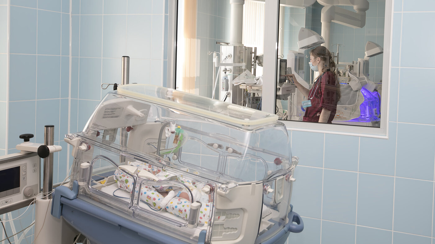 Bildet viser et nyfødt barn som ligger i en inkubator