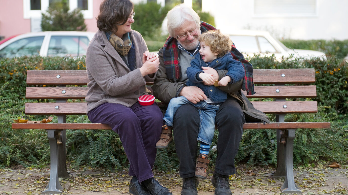 Bildet viser et eldre par og et barn som sitter på en benk