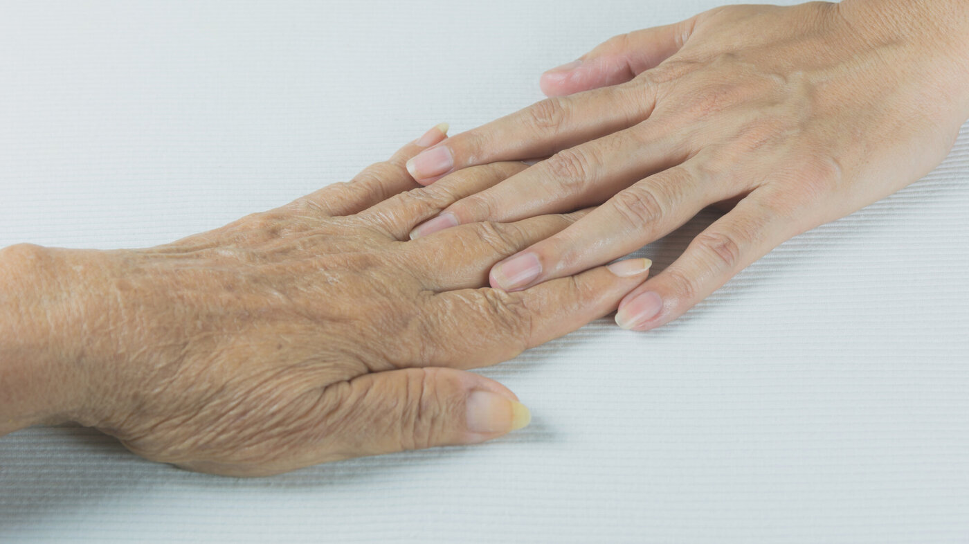 Bilde av en ung hånd som berører en gammel hånd.