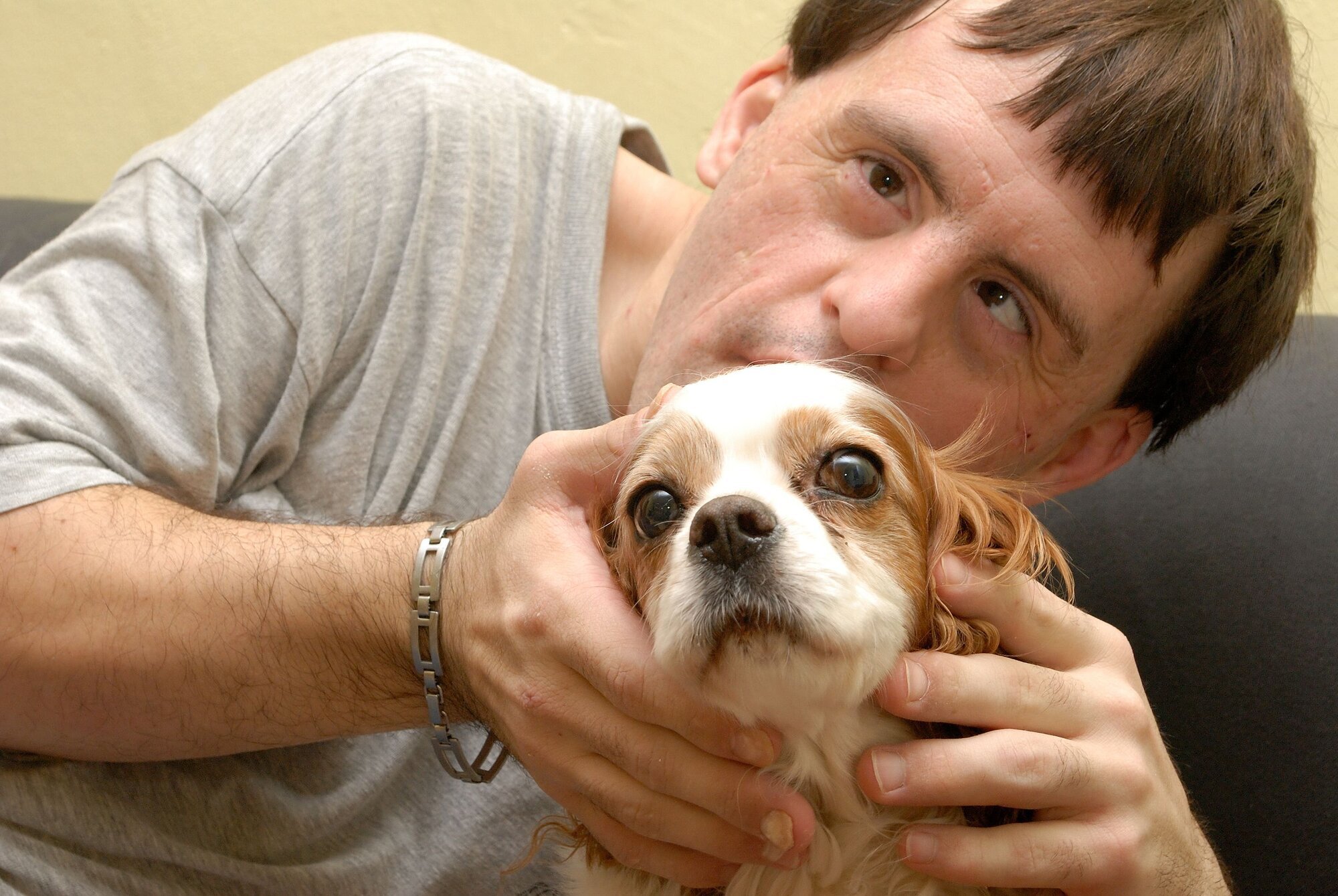 Mann med Downs syndrom stryker på en hund. Mann med Downs syndrom koser med en hund.