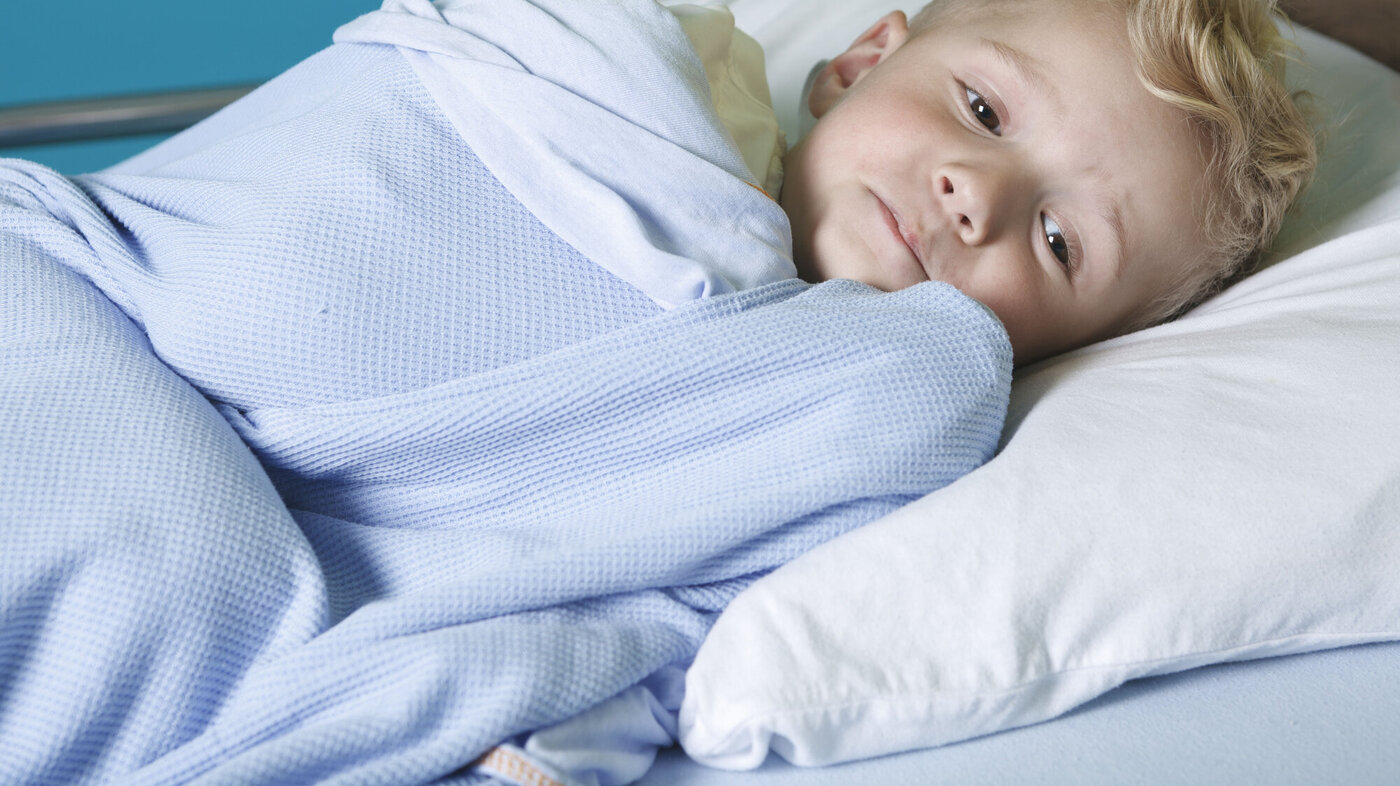 Bildet viser en syk, liten gutt i en sykehusseng.