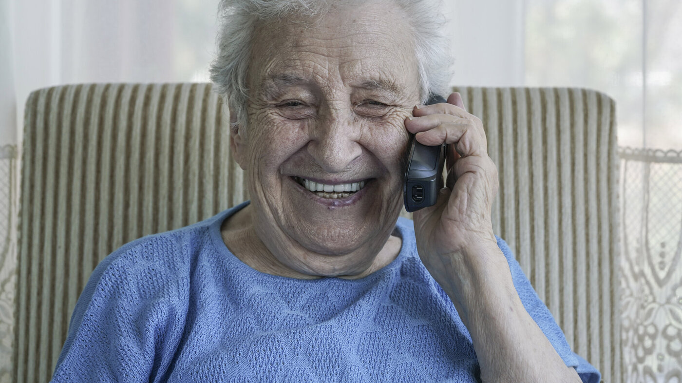 Bildet viser en fornøyd eldre kvinne som prater i telefonen