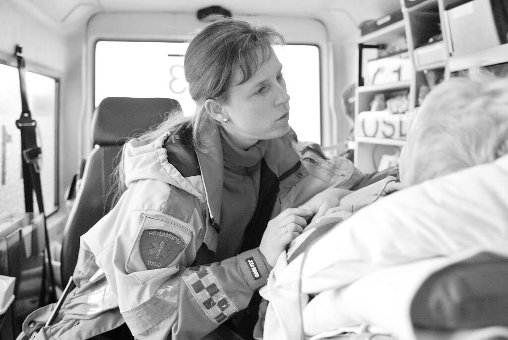 Sykepleier overvåker pasient i ambulanse Sykepleier overvåker pasient i ambulanse