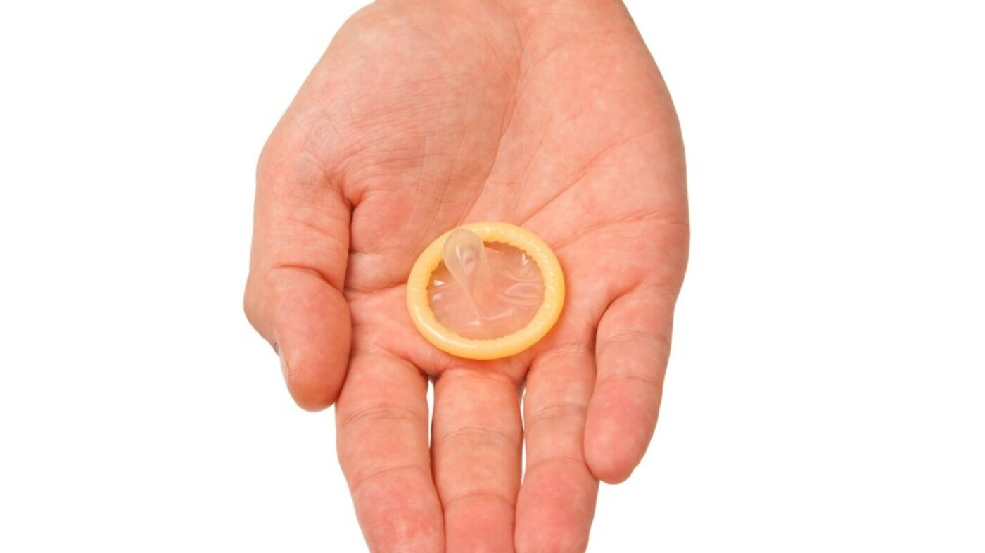 Bildet viser en hånd som holder frem et kondom