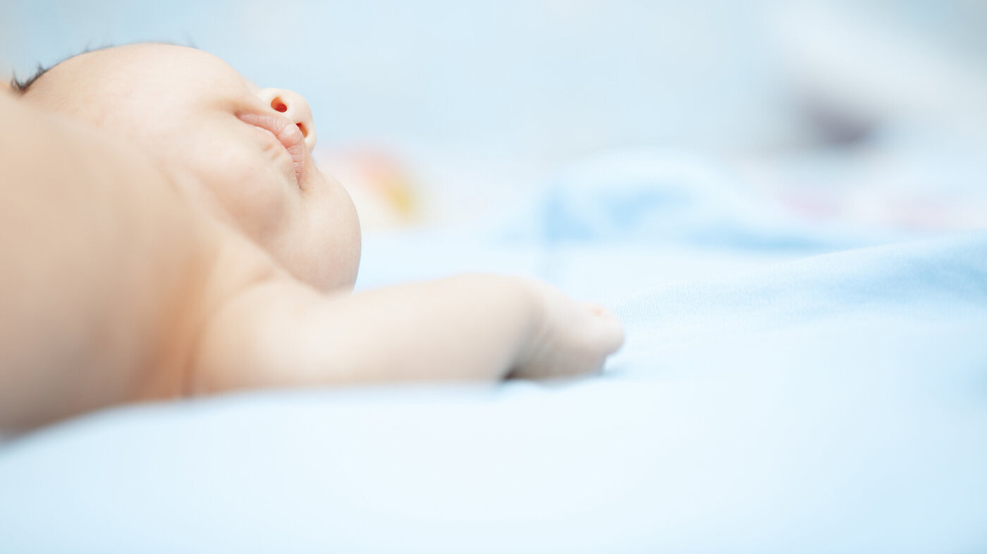 Bildet viser en guttebaby på lyseblått teppe.