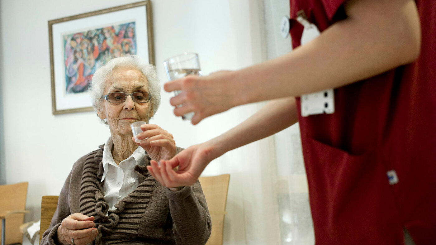 Eldre dame Bildet viser en eldre kvinne som får utdelt medisiner