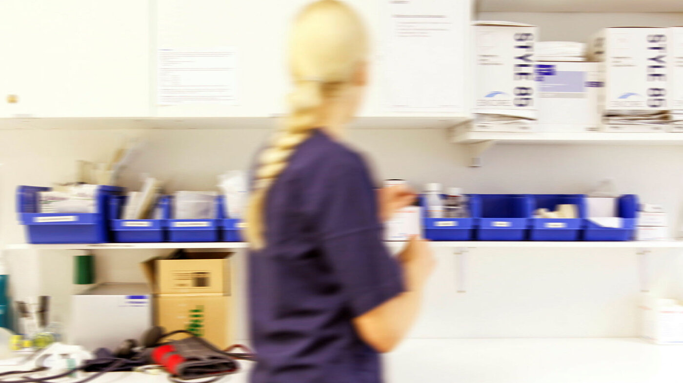 Bildet viser en sykepleier som finner frem medisiner på et medisinrom.