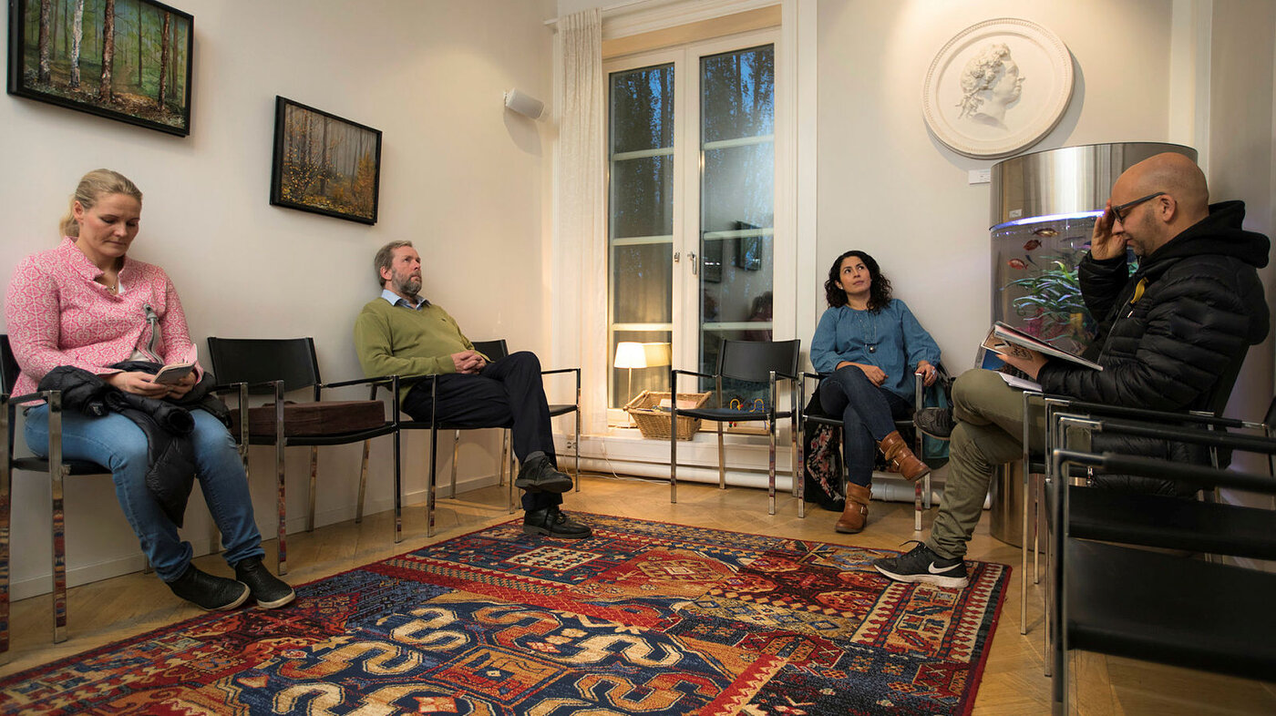 Bildet viser fire personer som sitter i et venterom