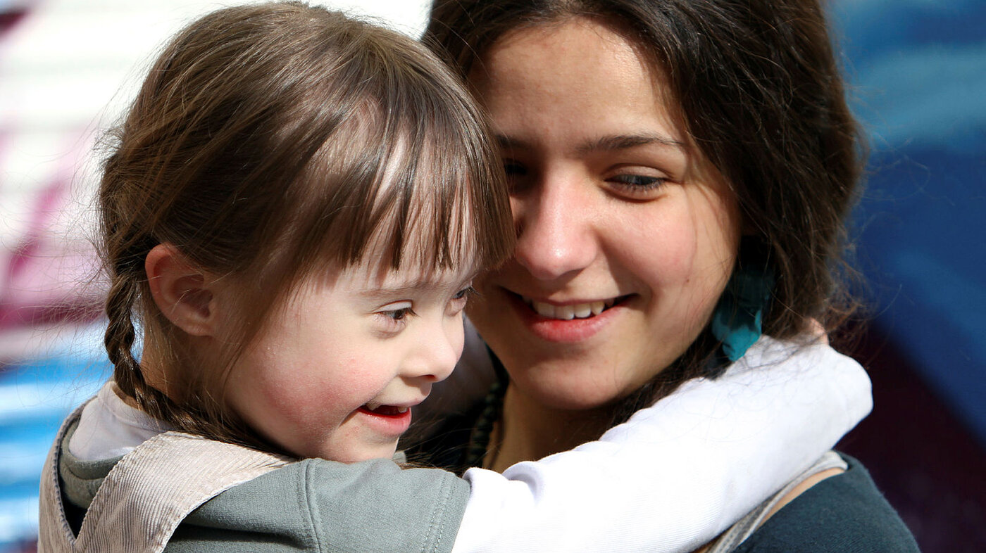 Bildet viser en lykkelig mor som holder en glad datter, som har Downs syndrom