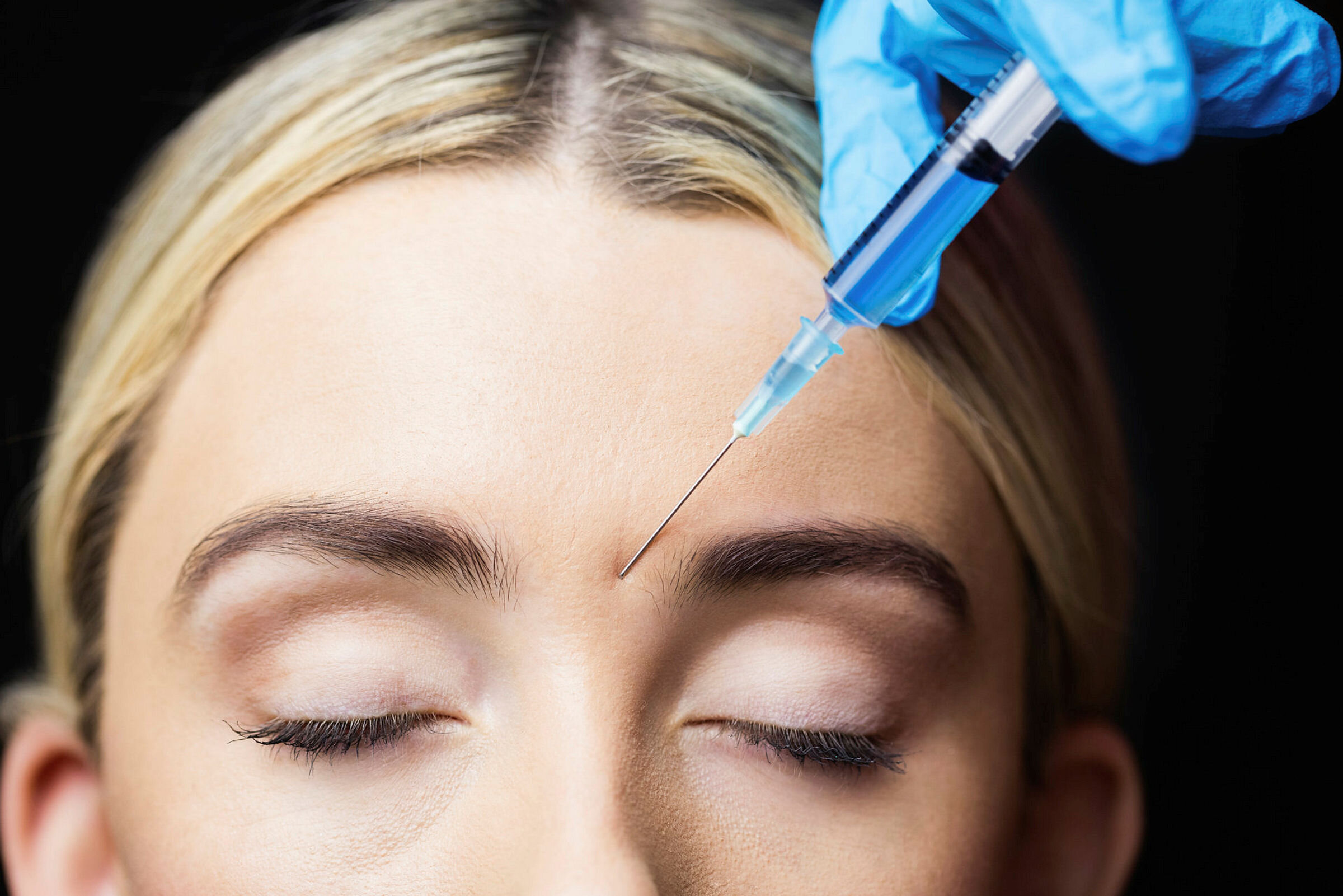 Woman receiving botox injection on her forehead Woman receiving botox injection on her forehead in a examination room
