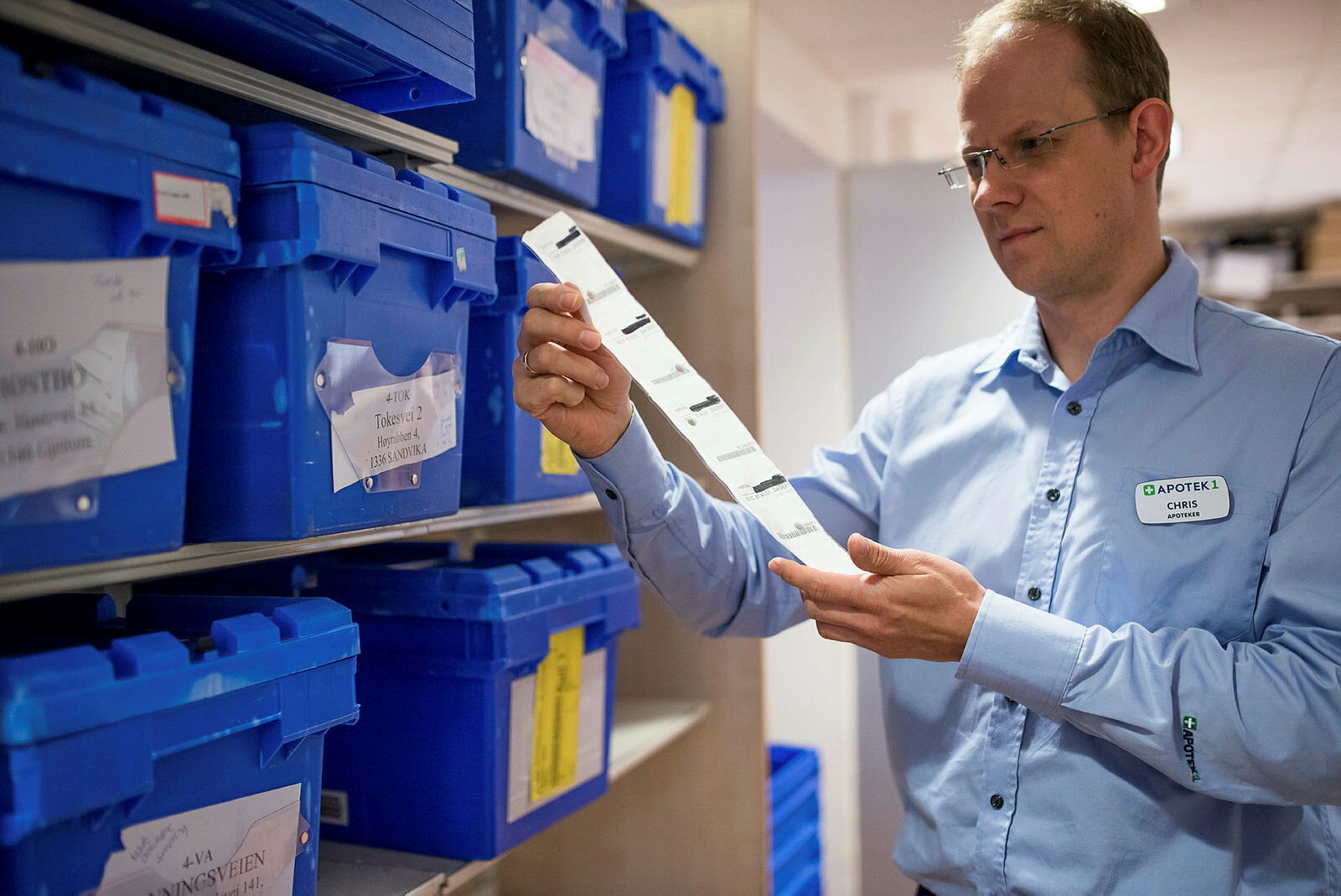 Multidoseposer Apoteker Chris Jacobs ved Apotek 1 Asker holder opp en remse med multidoseposer.