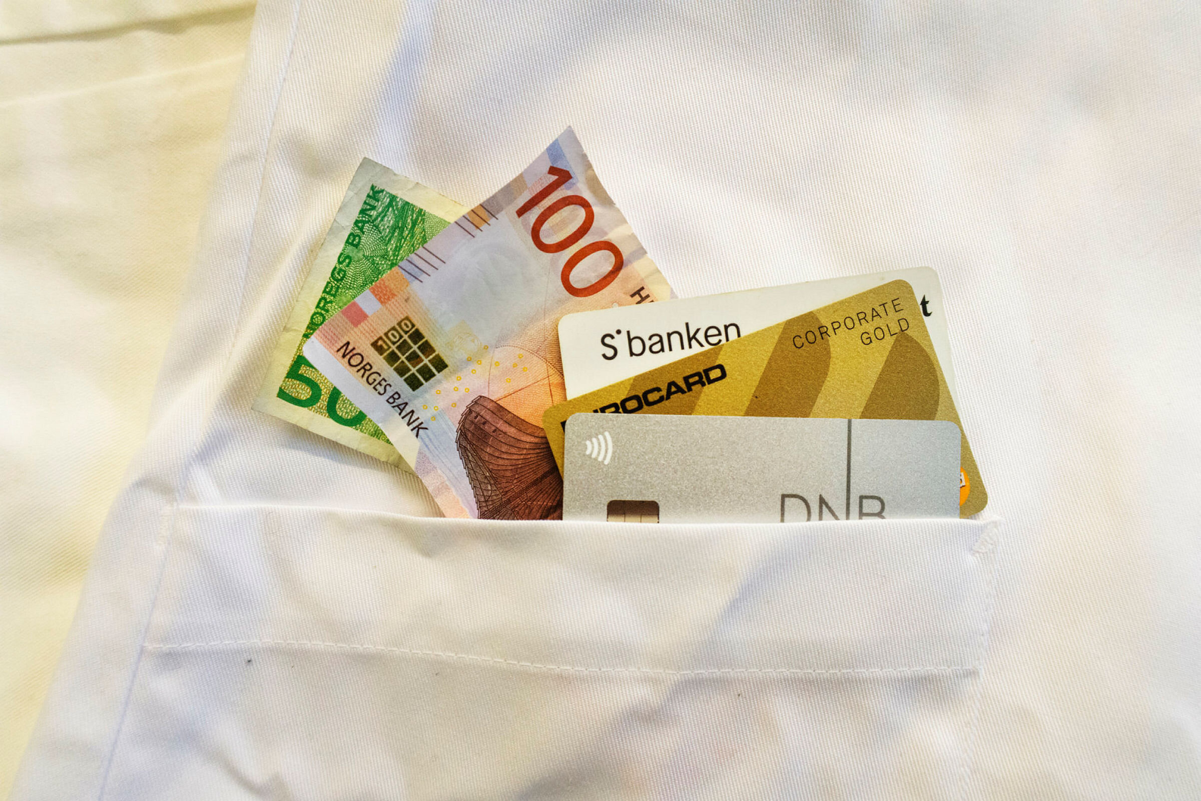 Penger og bankkort Penger og bankkort i lommen på en sykepleieruniform