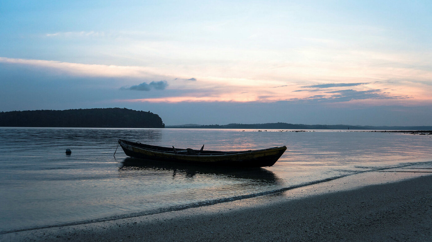 Bildet viser en båt som ligger ved en strand om kvelden
