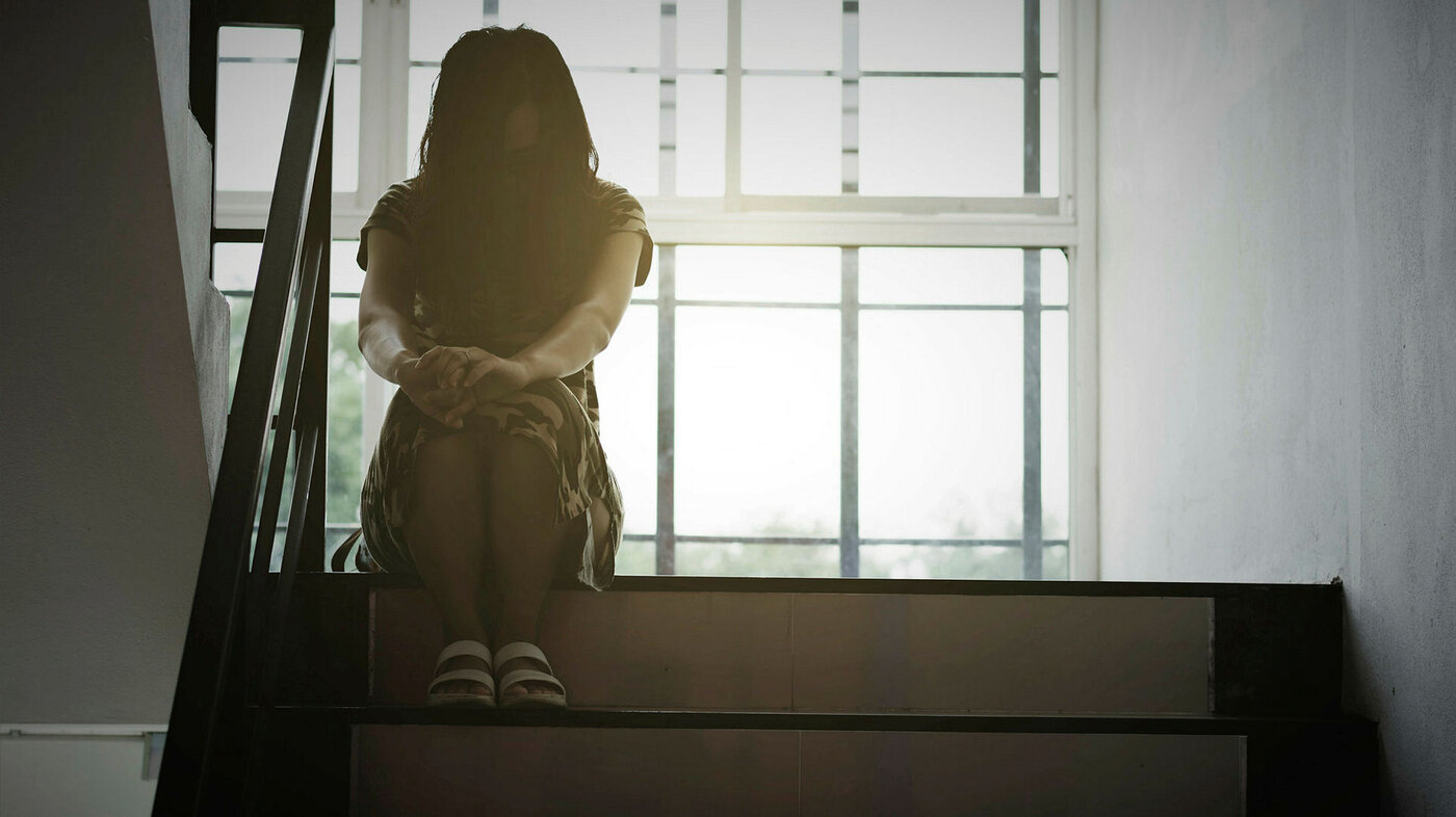 En anonym kvinne sitter i en trappeoppgang