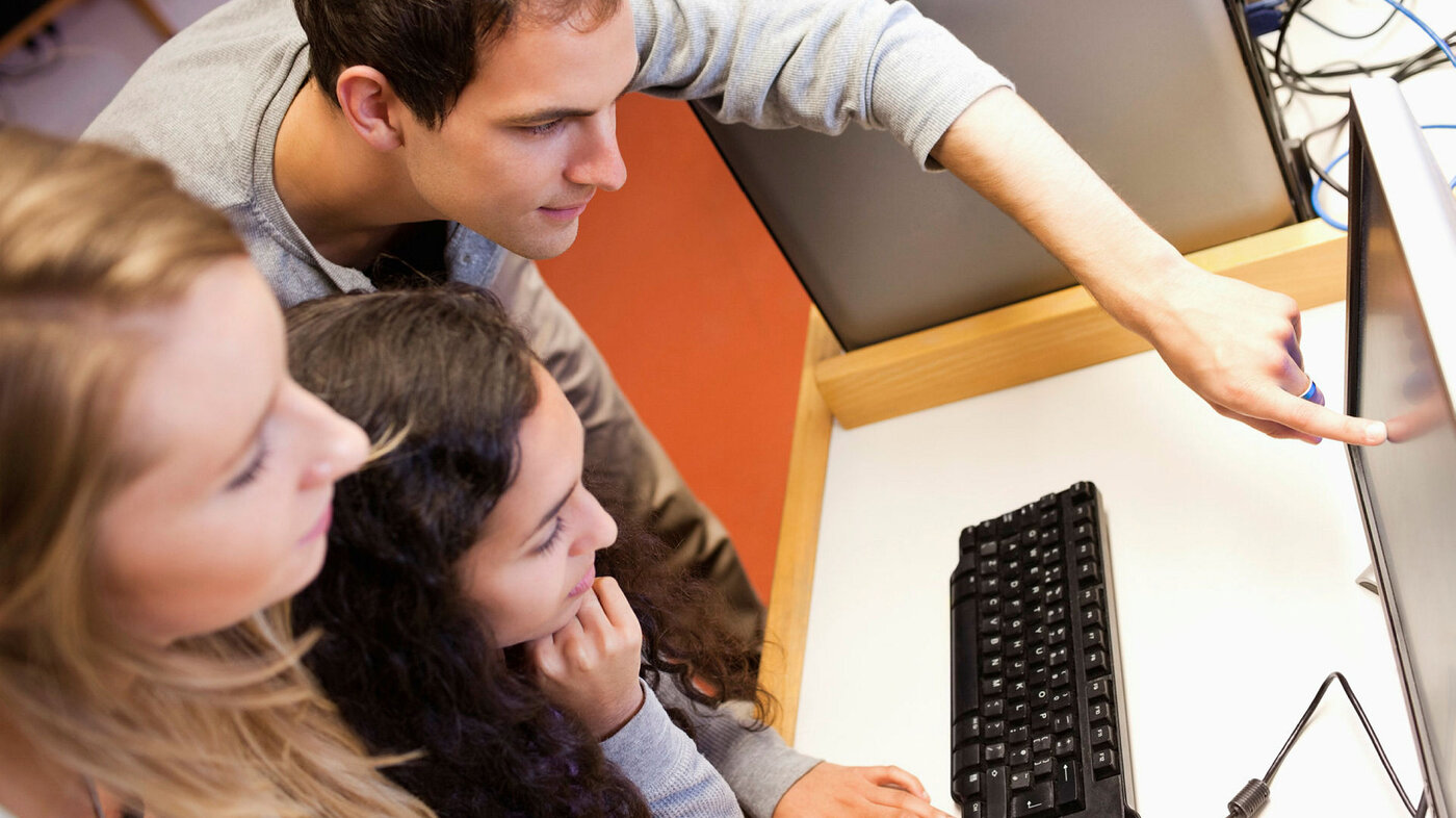 Studenter Tre unge mennesker ser på en pc.