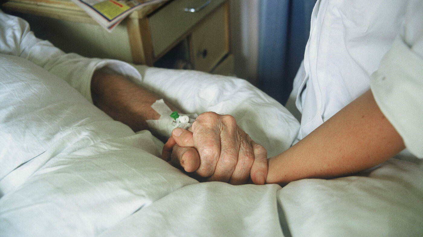 Sykepleier holder eldre pasient i  hånden