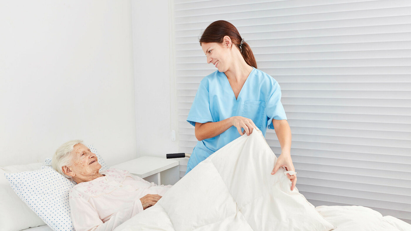 Bildet viser en sykepleier som steller for en syk pasient.