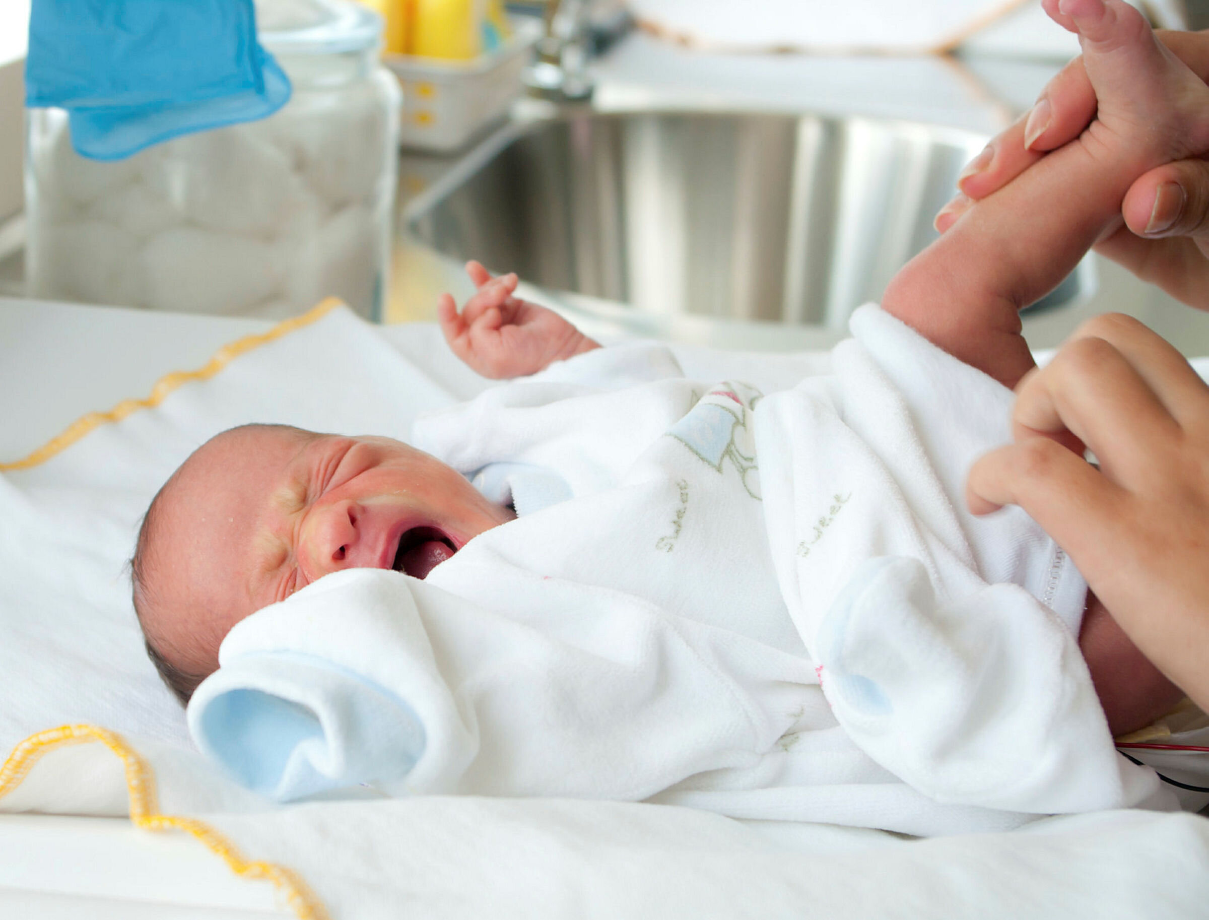 Skrikende baby Bildet viser en baby som blir stelt og skriker.