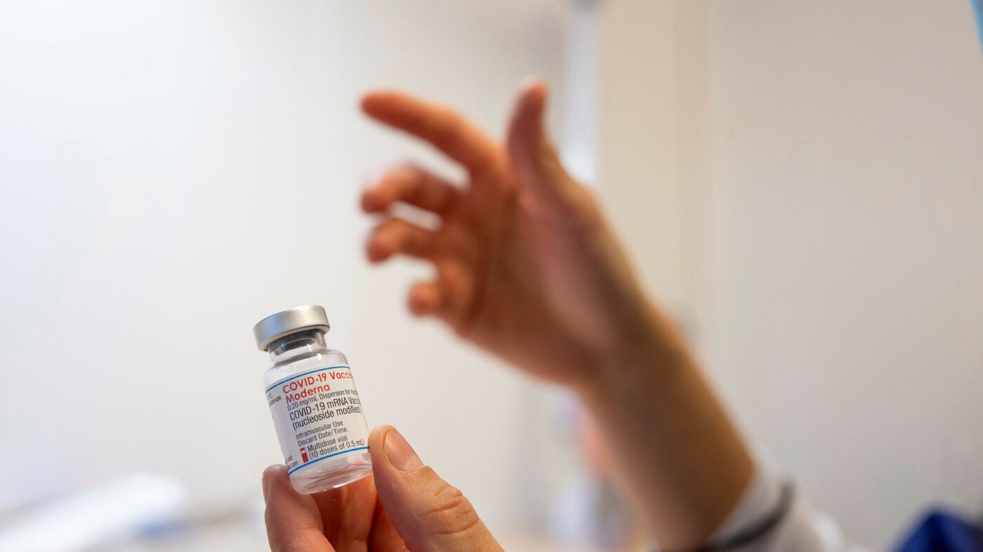 Koronavaksine Bildet viser hender som holder et hetteglass med vaksine.
