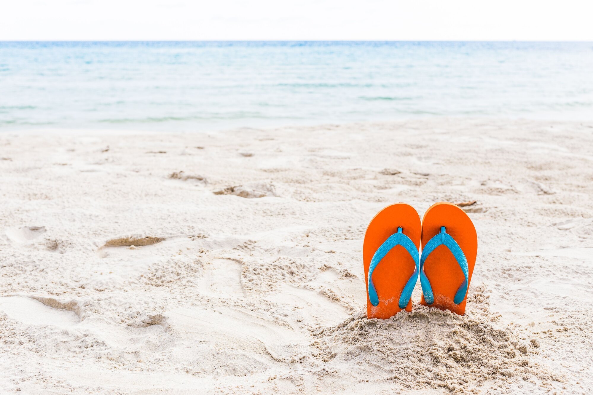 Sommer Bilde av strand med badesko stikkende opp av sanden