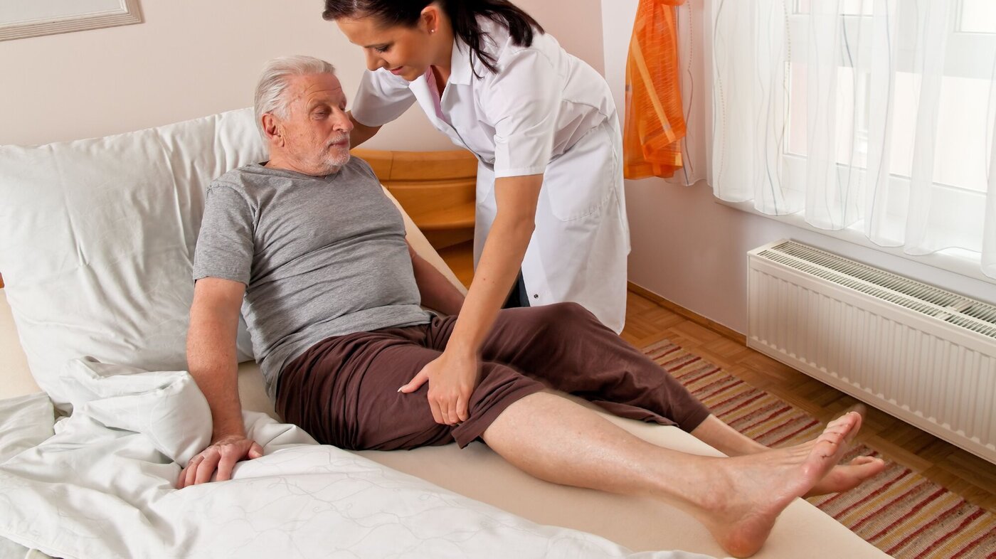 Illustrasjonsfoto av sykepleier som hjelper en pasient ut av senga