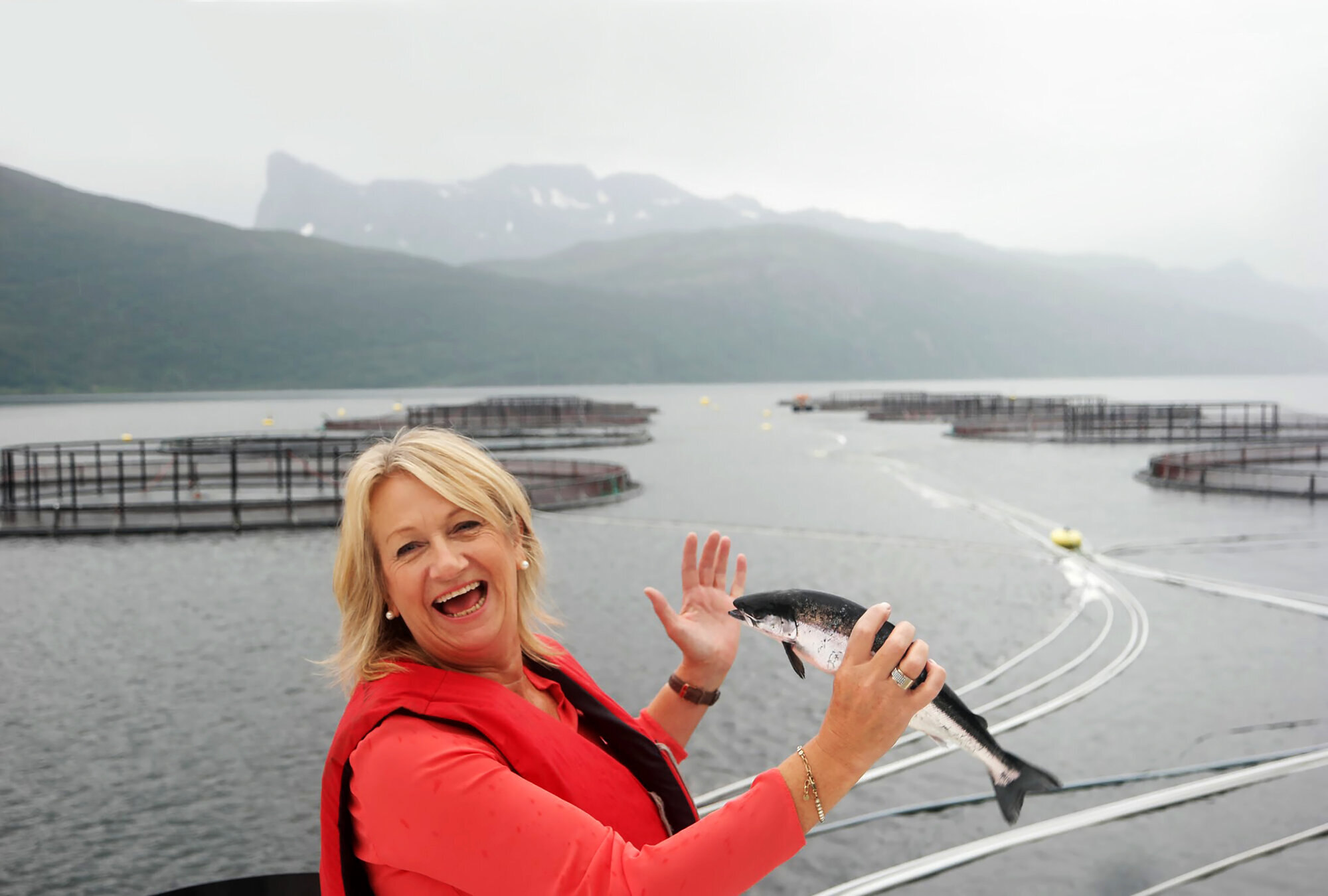 Fiskeoppdrett Torill er ute ved et fiskeoppdrettsanlegg. Hun holder en fisk i hånden.