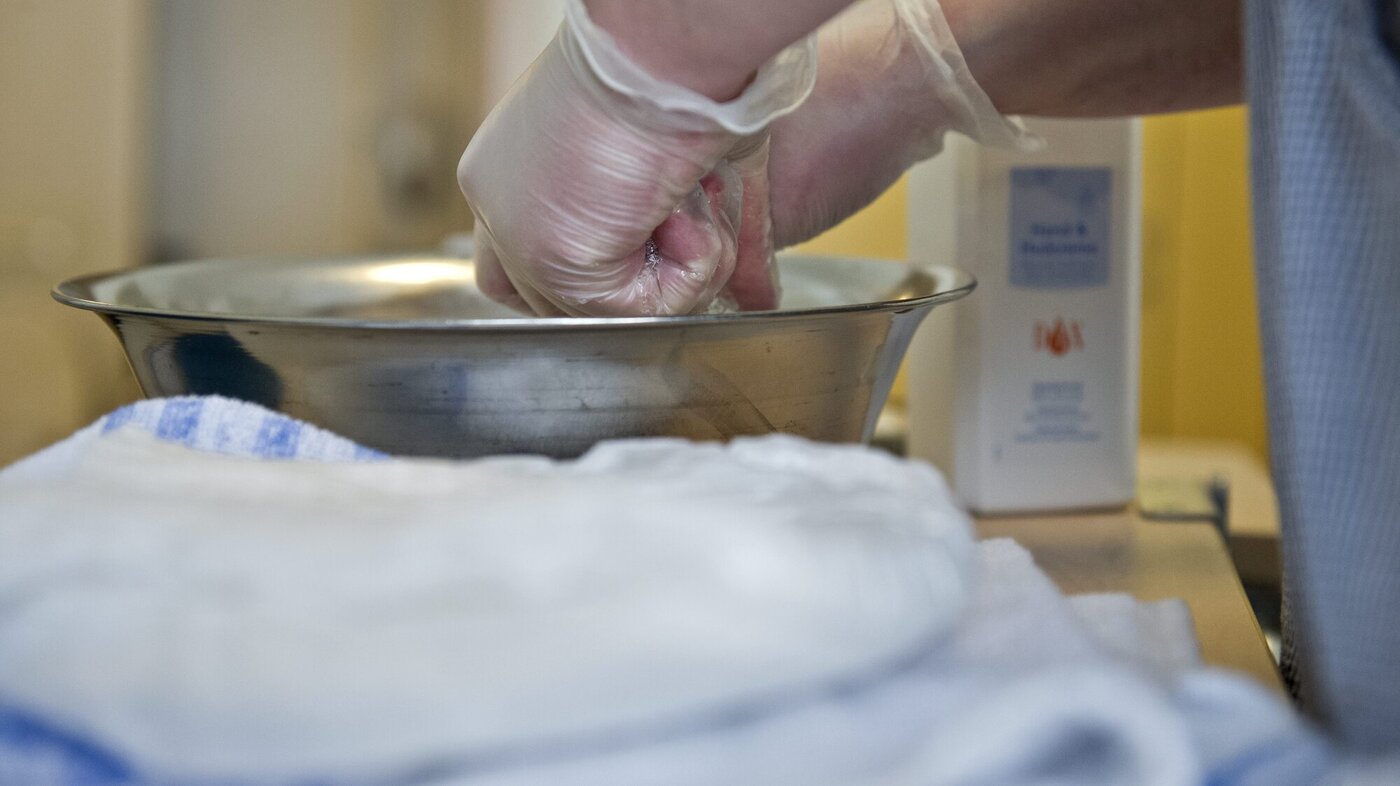 En pleier på en helseinstitusjon gjør klar til vasking av pasient. 