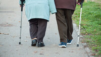 Et eldre par med spaserstokk går tur