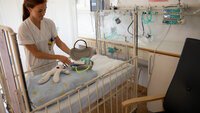 Bildet viser en sykepleier som legger frem en dukke og et førstehjelpsskrin laget av pussbekken.