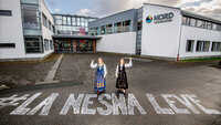 Bildet viser to bunadskledte mennesker utenfor høgskolen i Nesna, på bakken er det skrevet "La Nesna leve".