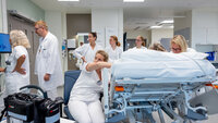 bildet viser mange helsepersonell rundt en pasient