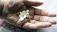 Bildet er et nærbilde av en hånd som holder ulike piller.