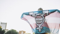 Bildet viser en person som holder opp et flagg med kjønnssymboler
