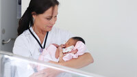 Bildet viser Kariann Turøy Bakstad med en nyfødt baby på armen
