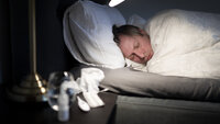 Bildet viser en forkjølet mann som ligger i sengen