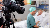 Bildet viser en anestesisykepleier som sitter på sengen med med en dukke som simulerer pasient