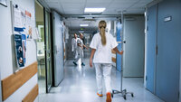 Bildet viser en sykepleier som går i en sykehuskorridor