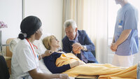 Bildet viser en pasient sammen med pårørende og helsepersonell.