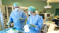 Bildet viser en kirurg og en sykepleier som forbereder medisinsk utstyr før en operasjon.