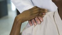 Hånden til en farget kvinne holder hånden til hvit mann.