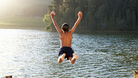 Bildet viser en ung gutt som hopper ut i et vann