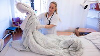 Bildet viser avdelingsvert som rer seng på medisinsk sengepost Sandnessjøen