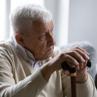 En eldre mann holder en stokk