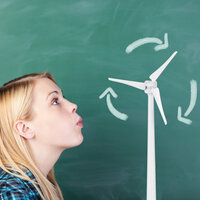 Bildet viser en jente i profil foran en tavle. Hun blåser på en krittegning av en vindturbin
