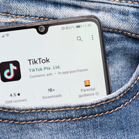 Bildet viser en mobil med TikTok som stikker opp av en bukselomme.
