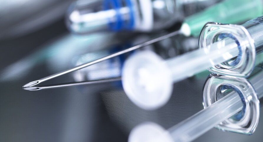 Bildet viser en kanyle og vaksiner på et brett.