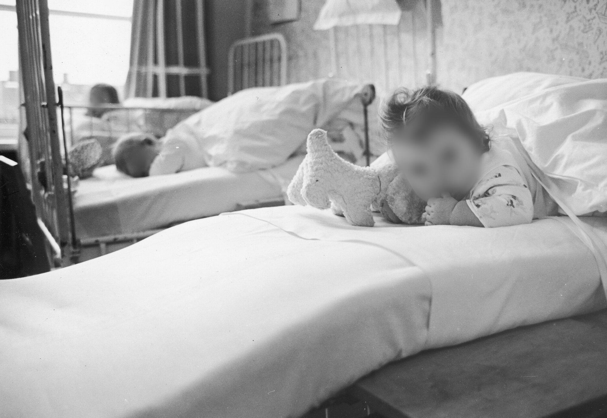 Bildet viser et lite barn som ligger i en sykehusseng.